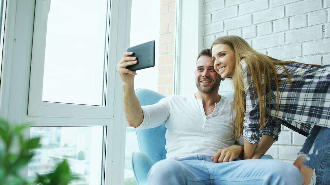 Young adults watching a streaming service on a tablet and smartphone in a living room